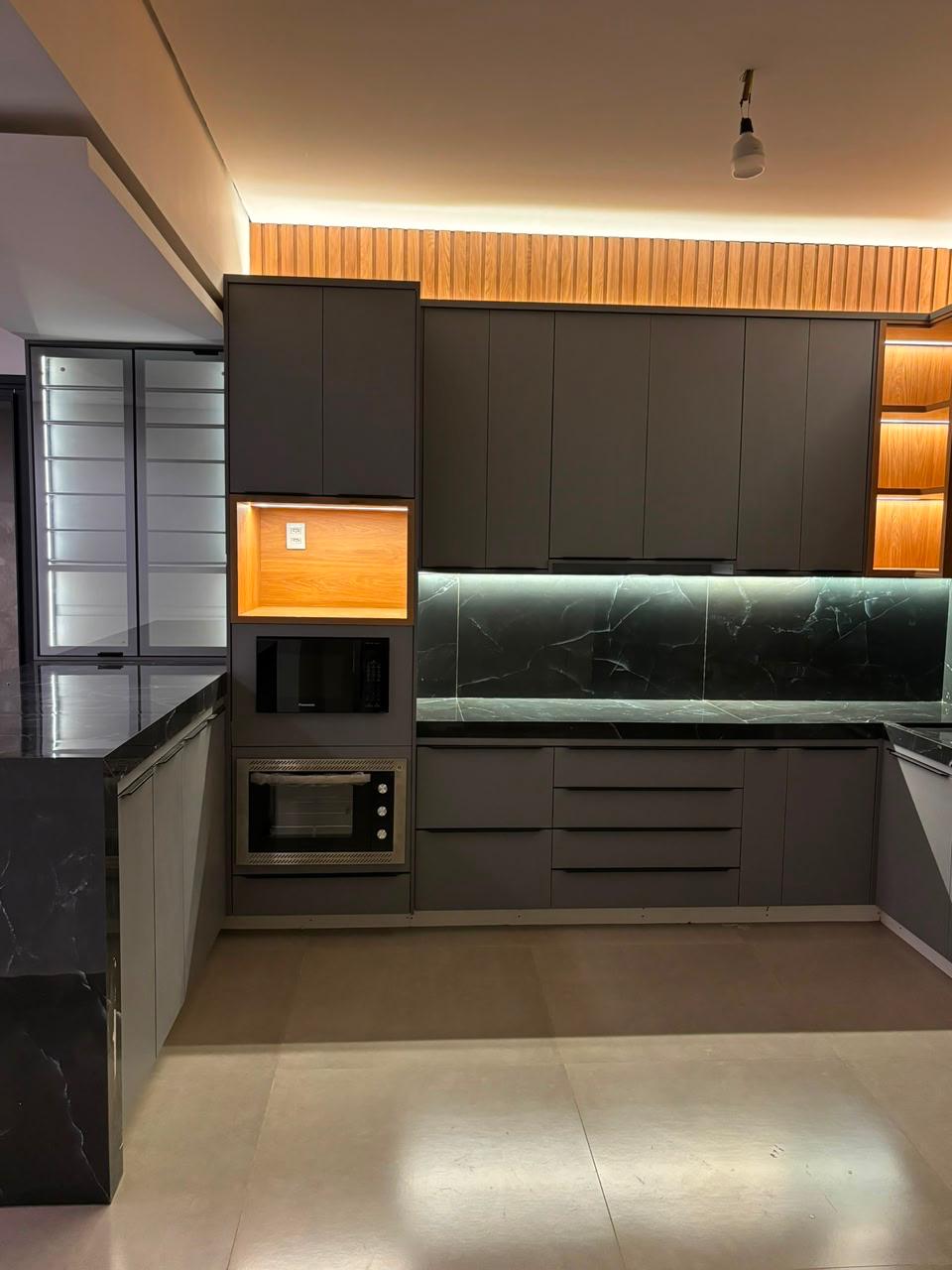 Cozinha em laca fosca grafite com backsplash em mármore escuro e luz de nicho